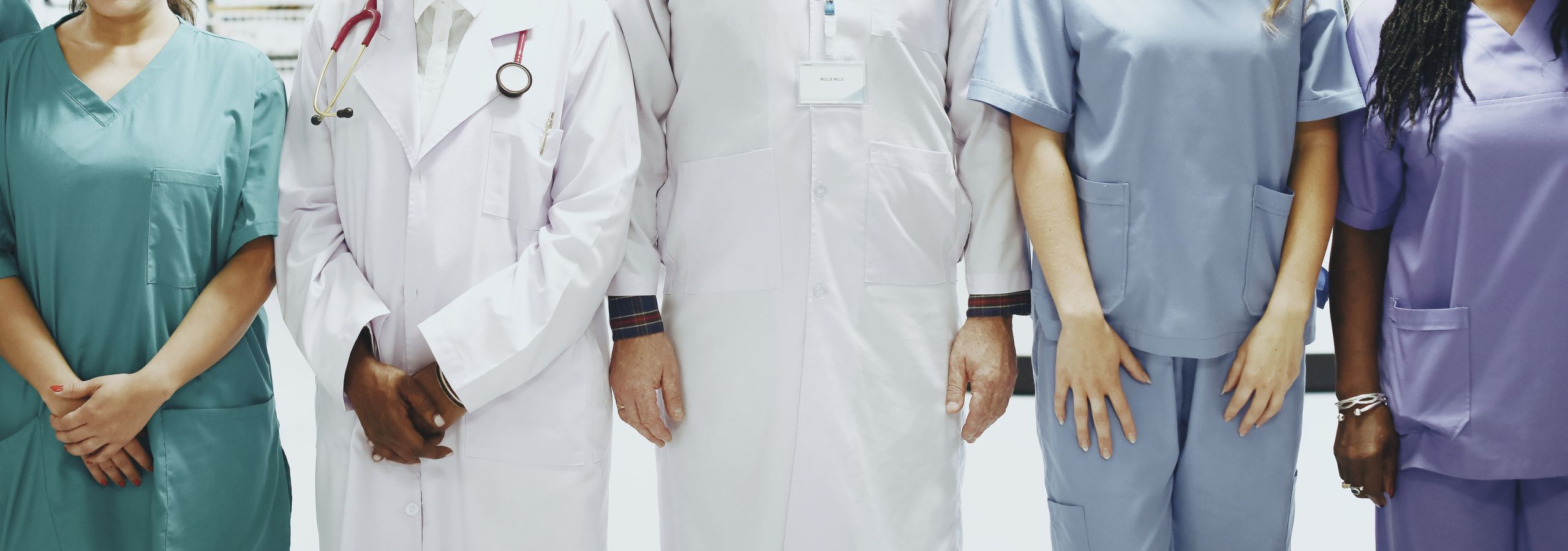 clinicians lined up in scrubs and white coats